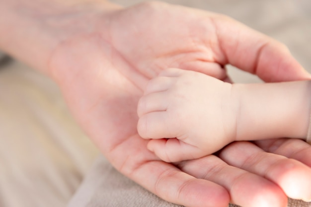 Mão com os dedos de um bebê recém-nascido e a mão da mãe.