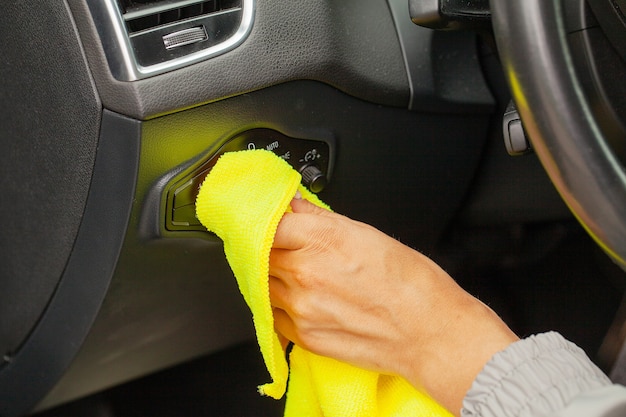 Mão com pano de microfibra para limpar Interior do carro moderno.