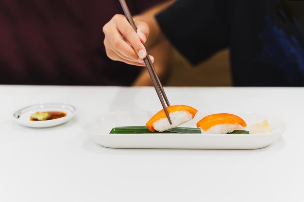 Mão com pauzinhos segura sushi com peixe salmão