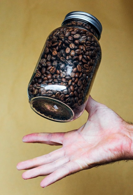 Mão com pote de vidro cheio de grãos de café