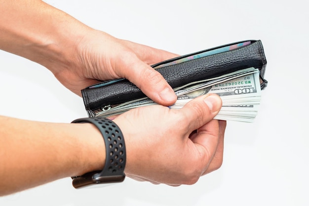 Mão com relógio segurando carteira preta com dólares