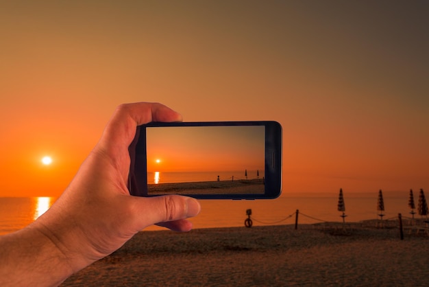 Mão com smartphone tirando fotos em um dia ensolarado