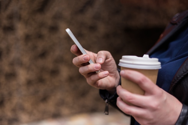 Mão com telefone e xícara de café