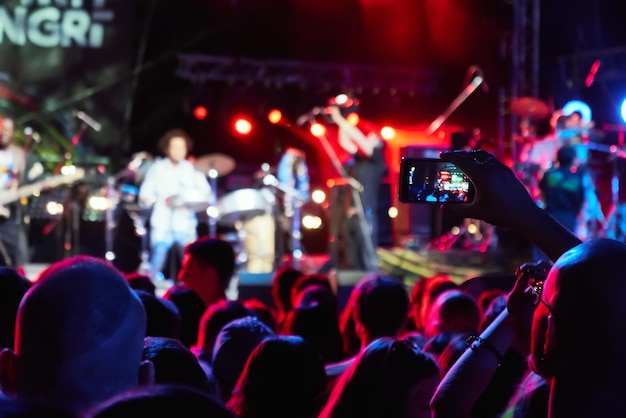 Foto mão com um smartphone grava festival de música ao vivo concerto ao vivo juventude feliz