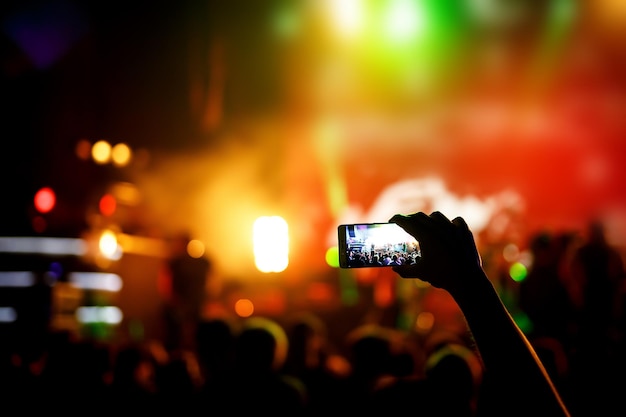 Mão com um smartphone grava show de concertos ao vivo do festival de música ao vivo no palco