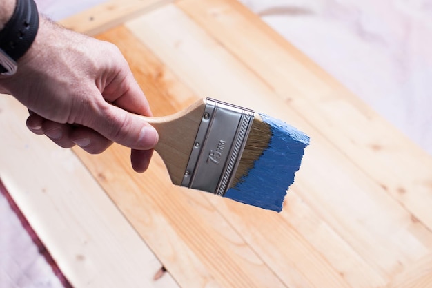 Mão com uma escova azul sobre a superfície de madeira