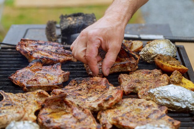 Foto mão cortada a colher carne na grelha de churrasco