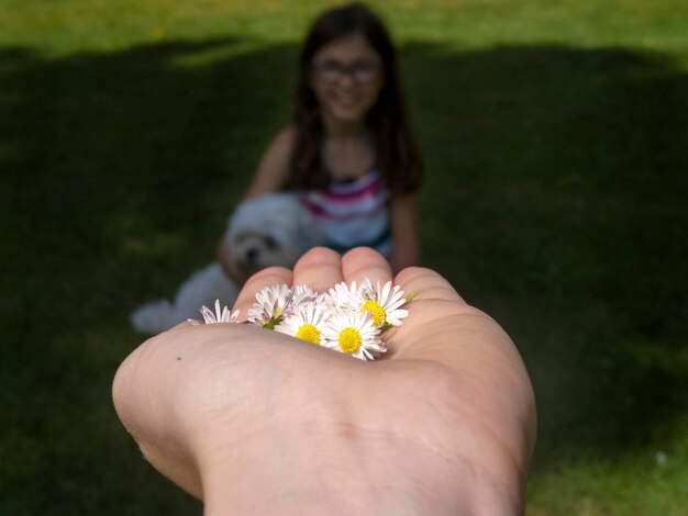 Foto mão cortada com flores contra mulher no fundo