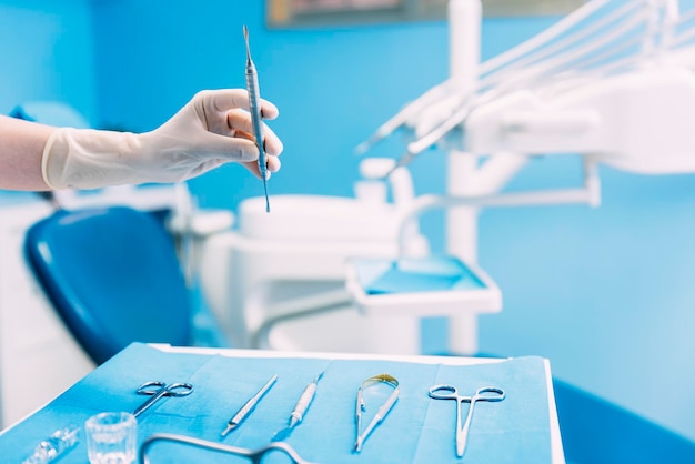 Mão cortada de dentista segurando equipamentos dentários na clínica