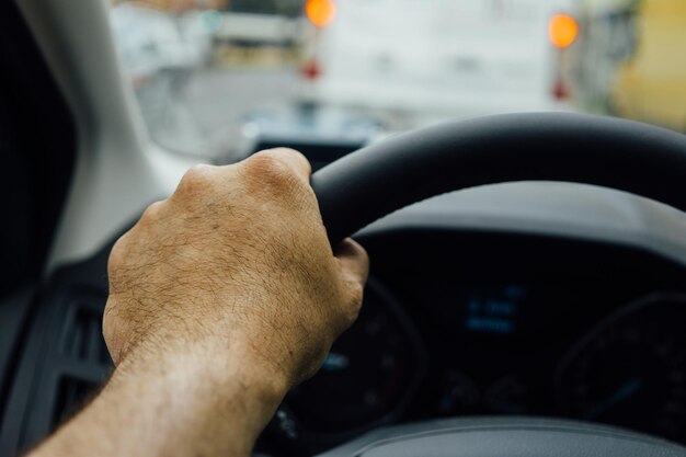 Foto mão cortada de homem a conduzir um carro.