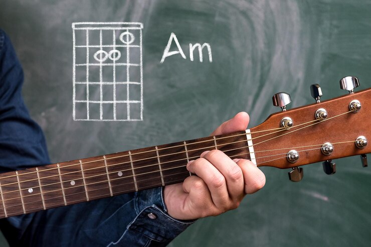 Foto mão cortada de homem tocando guitarra contra o quadro negro
