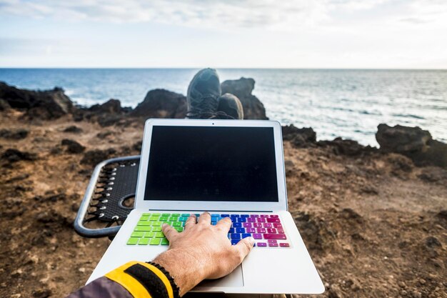 Foto mão cortada de homem tocando laptop na praia