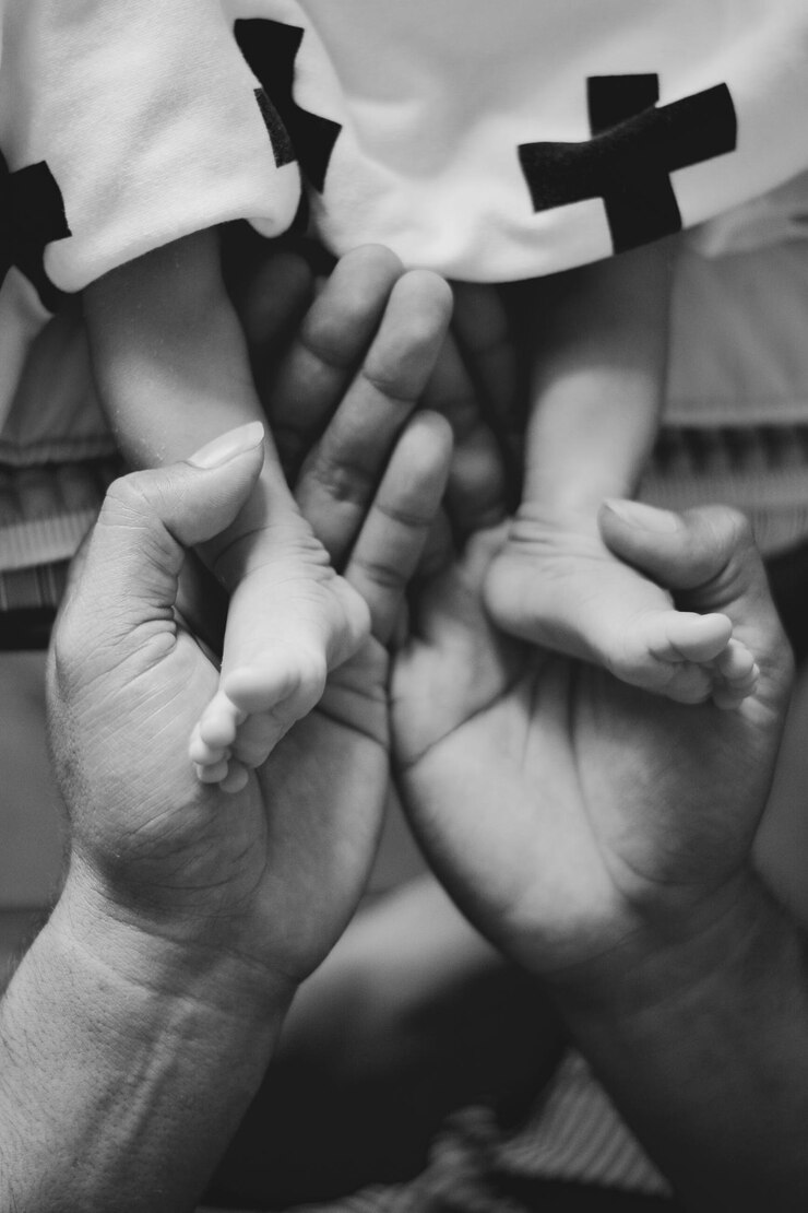 Foto mão cortada de mãe segurando as pernas da filha na cama