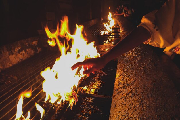 Foto mão cortada de mulher a alcançar a chama à noite.