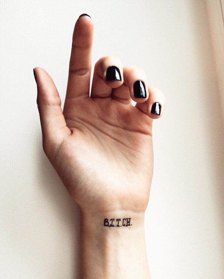 Foto mão cortada de mulher com tatuagem de puta na parede.