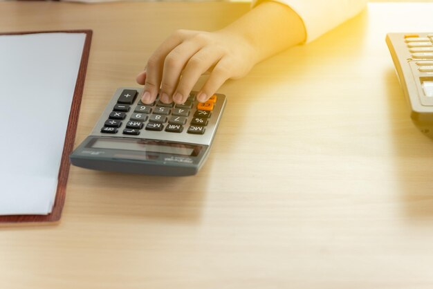 Mão cortada de mulher de negócios usando calculadora na mesa