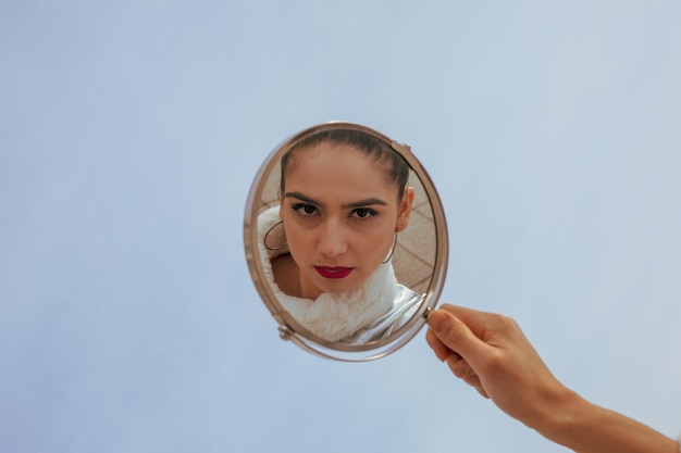 Foto mão cortada de mulher segurando espelho na cidade