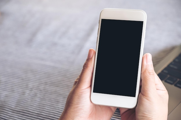 Mão cortada de mulher segurando telefone móvel na mesa