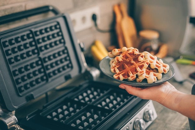Foto mão cortada de mulher segurando waffles em um prato