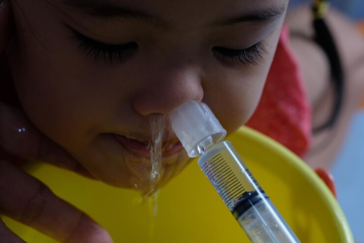Foto mão cortada de pai injetando medicamento no nariz da filha