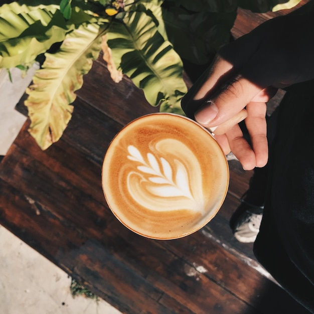 Foto mão cortada de pessoa segurando café sobre a mesa em casa