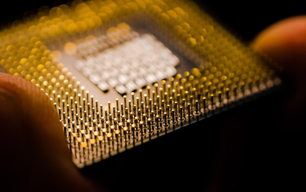 Mão cortada de pessoa segurando chip de computador na sala escura