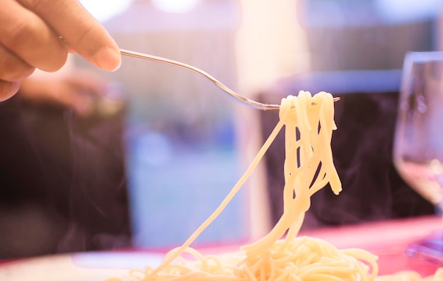 Foto mão cortada de pessoa segurando espaguete em garfo