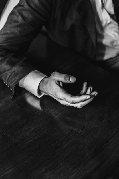 Foto mão cortada de um homem fazendo gestos em uma mesa de madeira