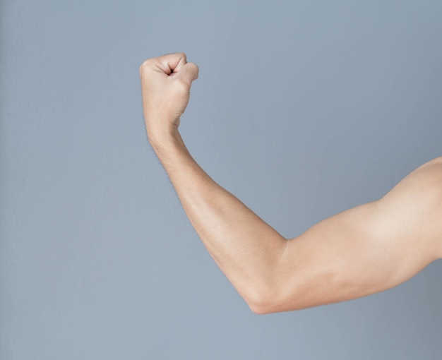 Mão cortada de um homem flexionando músculos sobre um fundo cinzento