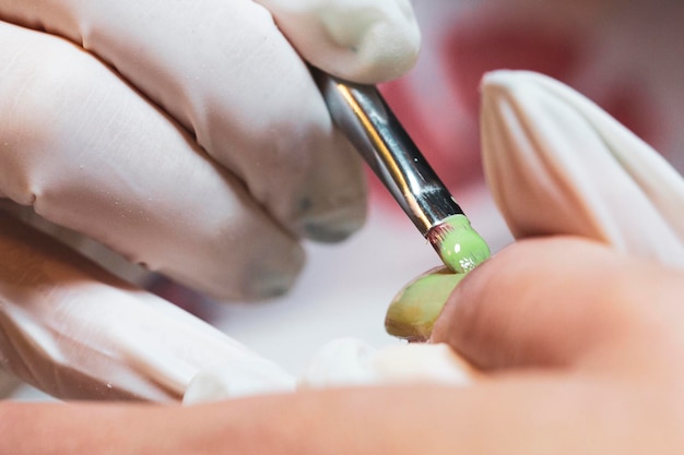 Mão cortada de uma esteticista a aplicar arte de unhas a uma mulher