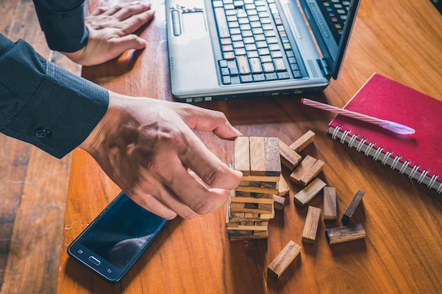 Foto mão cortada empilhando blocos de madeira por laptop na mesa