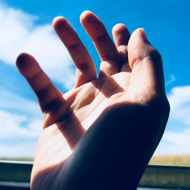 Foto mão cortada gesticulando contra o céu