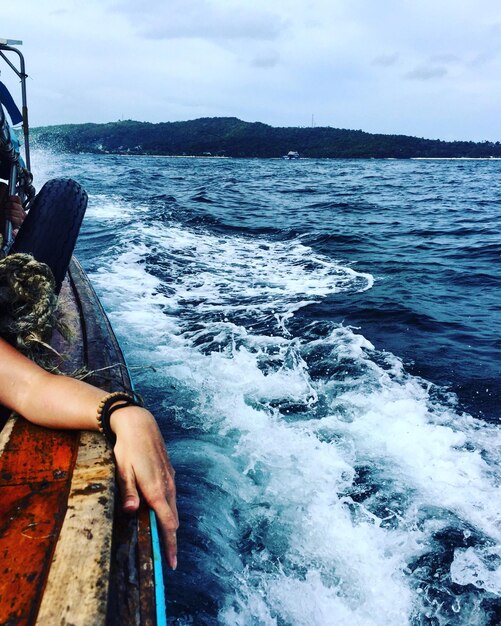 Foto mão cortada num barco no mar contra o céu