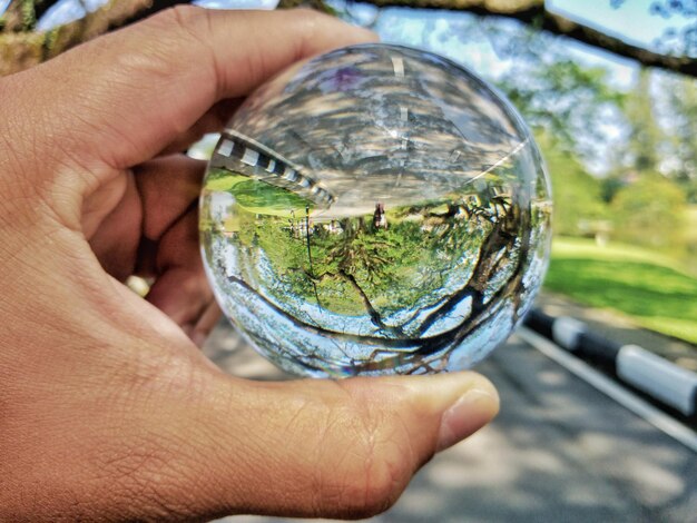 Mão cortada segurando bola de cristal com reflexo na estrada.