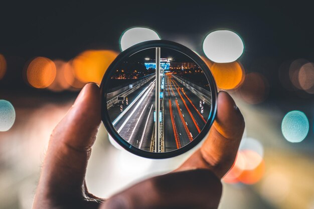 Foto mão cortada segurando espelho com reflexo na cidade