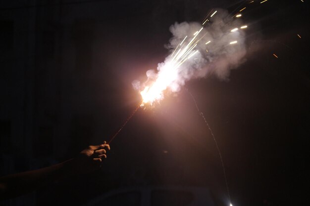 Mão cortada segurando exibição de fogos de artifício à noite