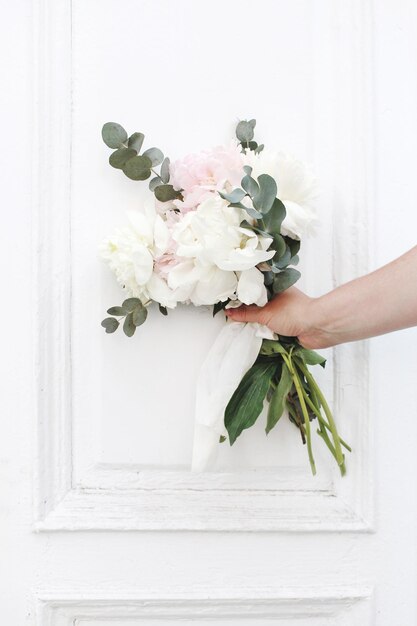 Foto mão cortada segurando flores brancas na porta