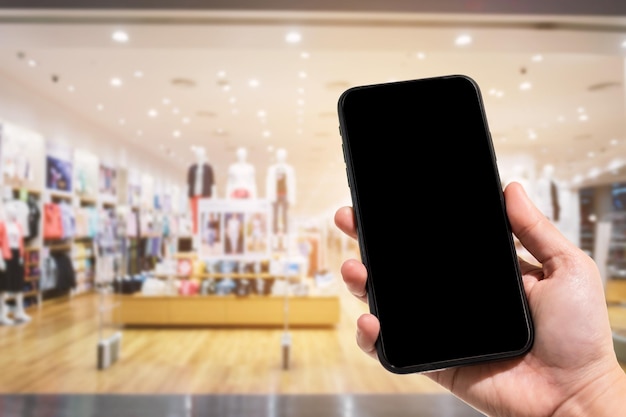 Foto mão cortada segurando telefone celular em um shopping