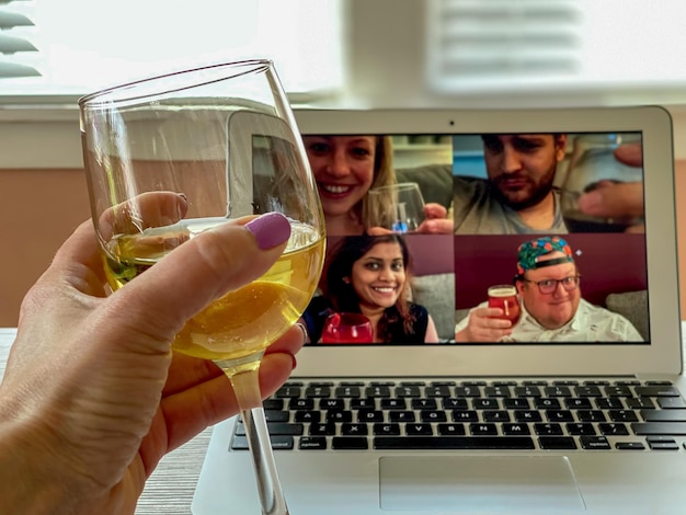Foto mão cortada segurando um copo de vinho contra o laptop