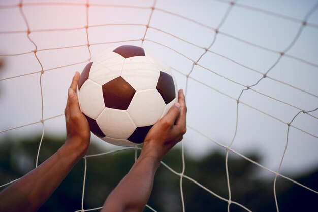 Foto mão cortada segurando uma taça de futebol na rede