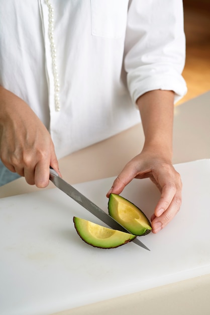 Mão cortando abacate fresco orgânico