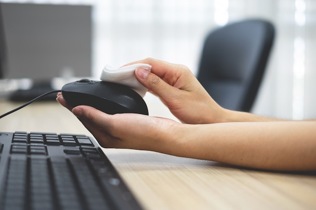 Mão da menina limpando o mouse do computador.