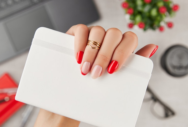 Foto mão da mulher com manicure da moda segurando o bloco de notas sobre a mesa, tendências de design de manicure
