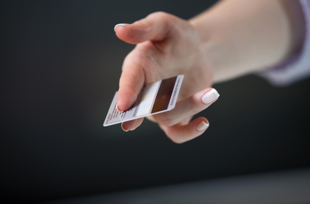 Mão da mulher esticando um cartão de crédito em gesto de oferta