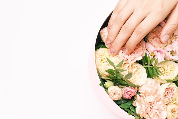 Mão da mulher na caixa com flores com espaço de cópia.