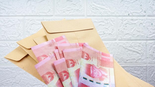 Mão da mulher que mostra o dinheiro indonésio Rupiah no envelope