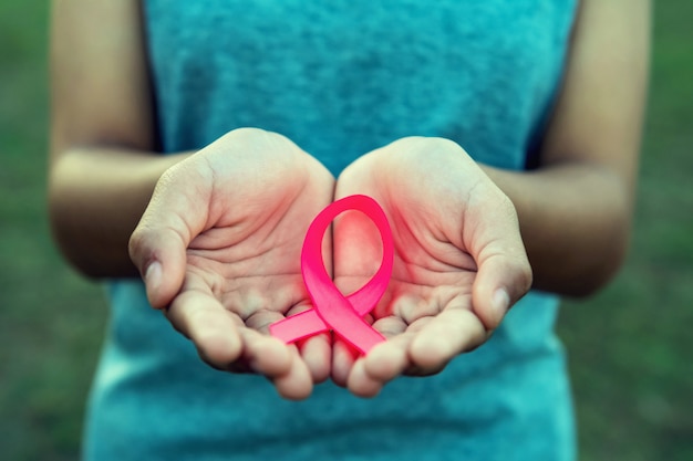 Mão da mulher que prende a consciência cor-de-rosa do cancro da mama da fita. cuidados de saúde conceito