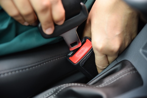 Mão da mulher que prende um cinto de segurança no carro. Conceito de segurança do carro.