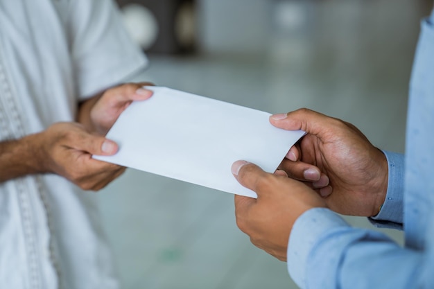 Mão dando envelope como doação de caridade na mesquita durante o ramadã