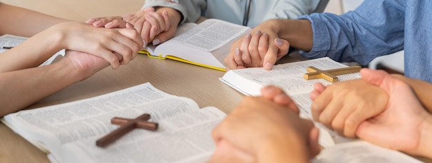 Foto mão de crente orando juntos em livro bíblico enquanto segurando a mão burgeoning